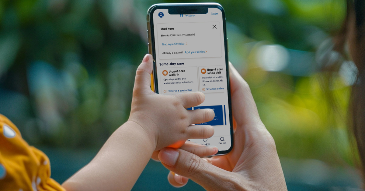 mother and child holding mobile phone with Children's Wisconsin app showing