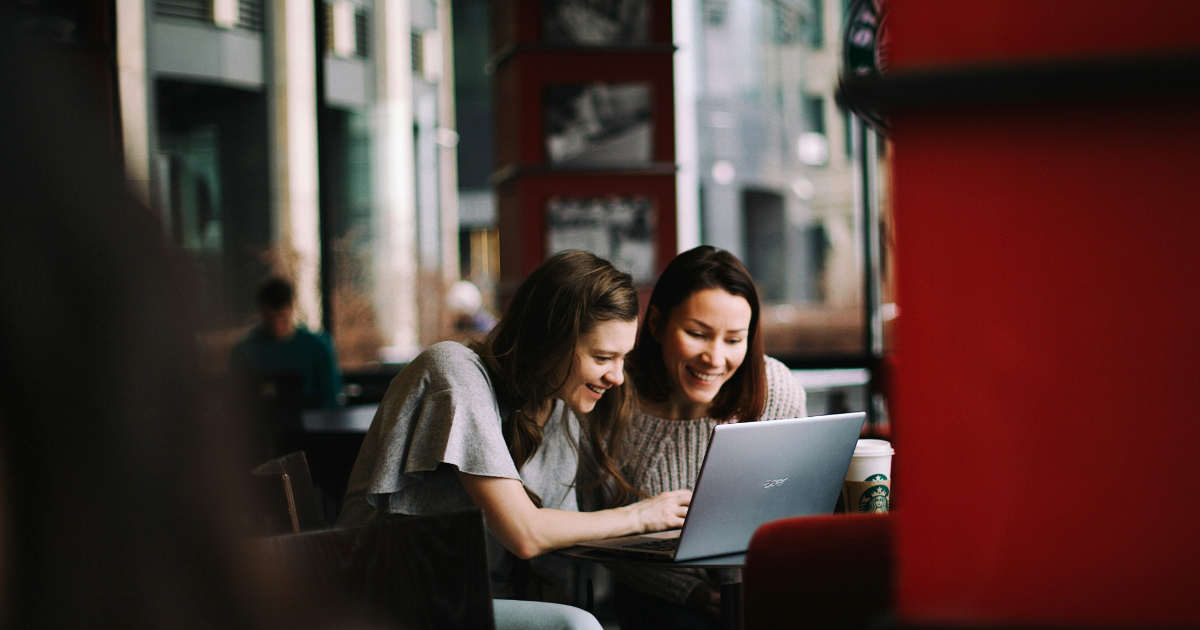 Two girls looking at a laptop and exploring Sitecore's XM Cloud features