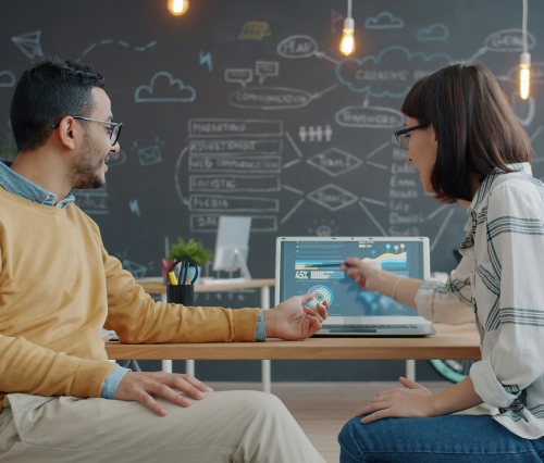 coworkers discussing analytics data on dashboard of laptop