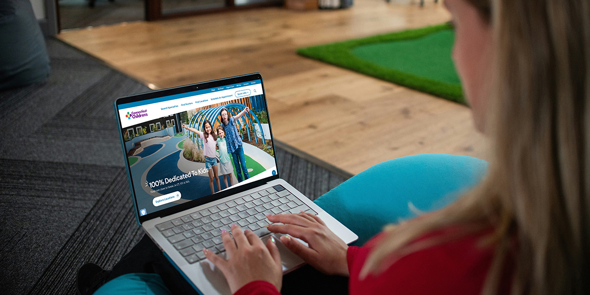 woman looking at Connecticut children's website on her laptop